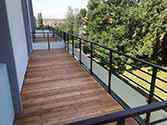 balcon avec lame de planches en bois et garde-corps avec remplissage en verre