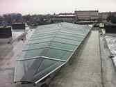 Toit en verre avec structure de soutien en acier posée sur le toit d'un immeuble résidentiel pour couvrir une ouverture de la cour intérieure.