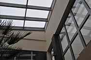 Toit en verre couvrant une serre dans un bâtiment de bureau. Panneaux de verre posés sur le dessus d'un cadre en acier galvanisé monté sur le toit.