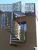Escalier en colimaçon avec structure de soutien d'inox et garde-corps avec des panneaux de tôle d'aluminium perforée thermolaqué