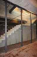 Cloison vitrée dans une cage d'escalier. Montée à l'aide des profilés en acier sur le plancher et le plafond. Panneaux de verre montés avec entretoises en inox