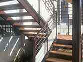 Escalier en acier, etapes de planches en bois et garde-corps avec remplissage en verre